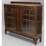 A 1930’s oak bookcase with low-stage panel back, with two adjustable shelves enclosed by a pair of