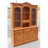 A pine dresser, the upper part fitted with an arrangement of shelves & two small drawers enclosed by