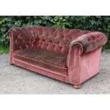 A buttoned-back three-seater chesterfield settee upholstered pink velour, & on bun feet, 72” long.