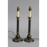 A pair of ebonised wooden table lamps, each with barley-twist column, round pedestal foot &