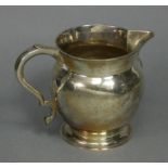 A George V silver round bulbous jug in the 18th century style, with short flared neck, scroll