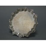 An Edwardian silver card tray with raised pie-crust & shell border, & on three scroll feet, 6”