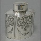 A late Victorian silver tea caddy of straight-sided lobed oval form, with embossed leaf-scroll