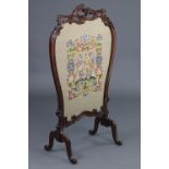 A Victorian carved mahogany firescreen, the pierced foliate scroll frame inset gros-point needlework