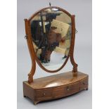 A Georgian mahogany toilet glass with shield-shaped mirror plate on shaped supports above a three-