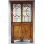 A George III mahogany standing corner cabinet with moulded cornice, fitted three shaped shelves