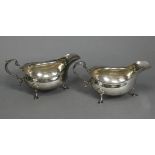 A pair of Georgian-style silver sauce boats with card-cut rims & scroll handles, each on three splay