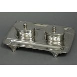 An Edwardian silver desk inkstand of rectangular form with reeded rims, a pen-trough either side,