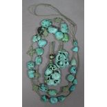 A Chinese necklace of natural turquoise beads with plaited silk knots at intervals, & pendant carved