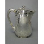 A Victorian silver hot-water jug of slender ovoid form, with engraved stylised foliate decoration,