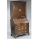 An 18th century oak bureau-bookcase, the upper part with moulded cornice, fitted two adjustable