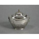 A late Victorian silver tea caddy of oval semi-fluted form, with hinged lid & lion-mask ring