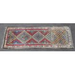 A Kilim runner with central row of five multicoloured lozenges within geometric borders; 9’9” x 3’