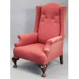 An early 20th century wing-back armchair in the early Georgian style, upholstered buttoned crimson