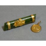 A New Zealand green jade-ite bar brooch with fern-leaf & NZ mount marked “9ct”, engraved bands
