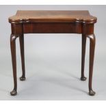 A GEORGE II ‘RED WALNUT’ CARD TABLE, the rectangular fold-over top with protruding rounded