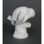 A Meissen white-glazed porcelain model of a bird perched on a tree stump, blue crossed swords &