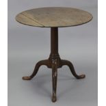 A late 19th century oak tripod table, with circular top on turned gun-barrel centre column & slender