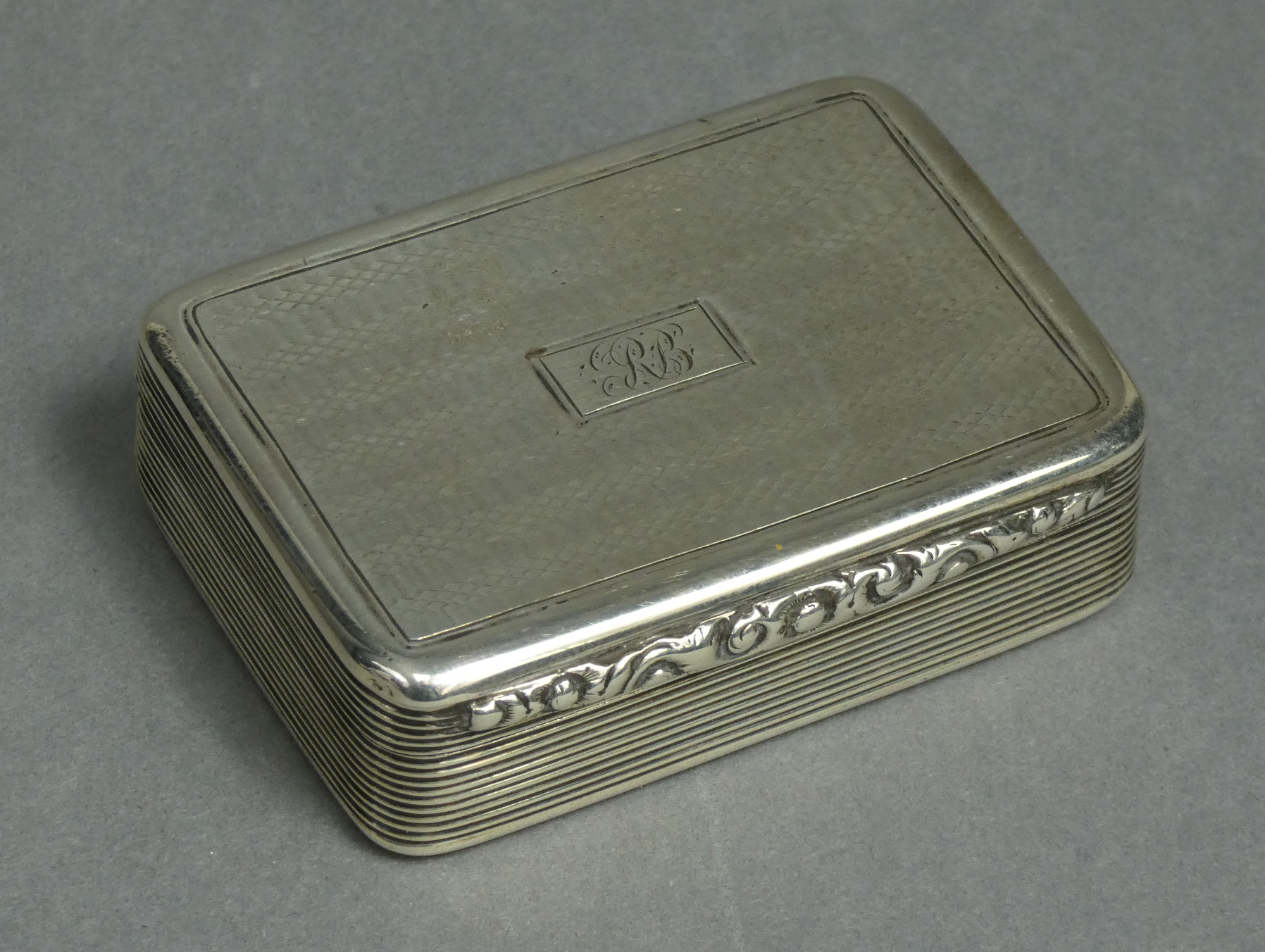 A William IV silver rectangular snuff box, engine-turned & with reeded sides, carved scroll thumb-