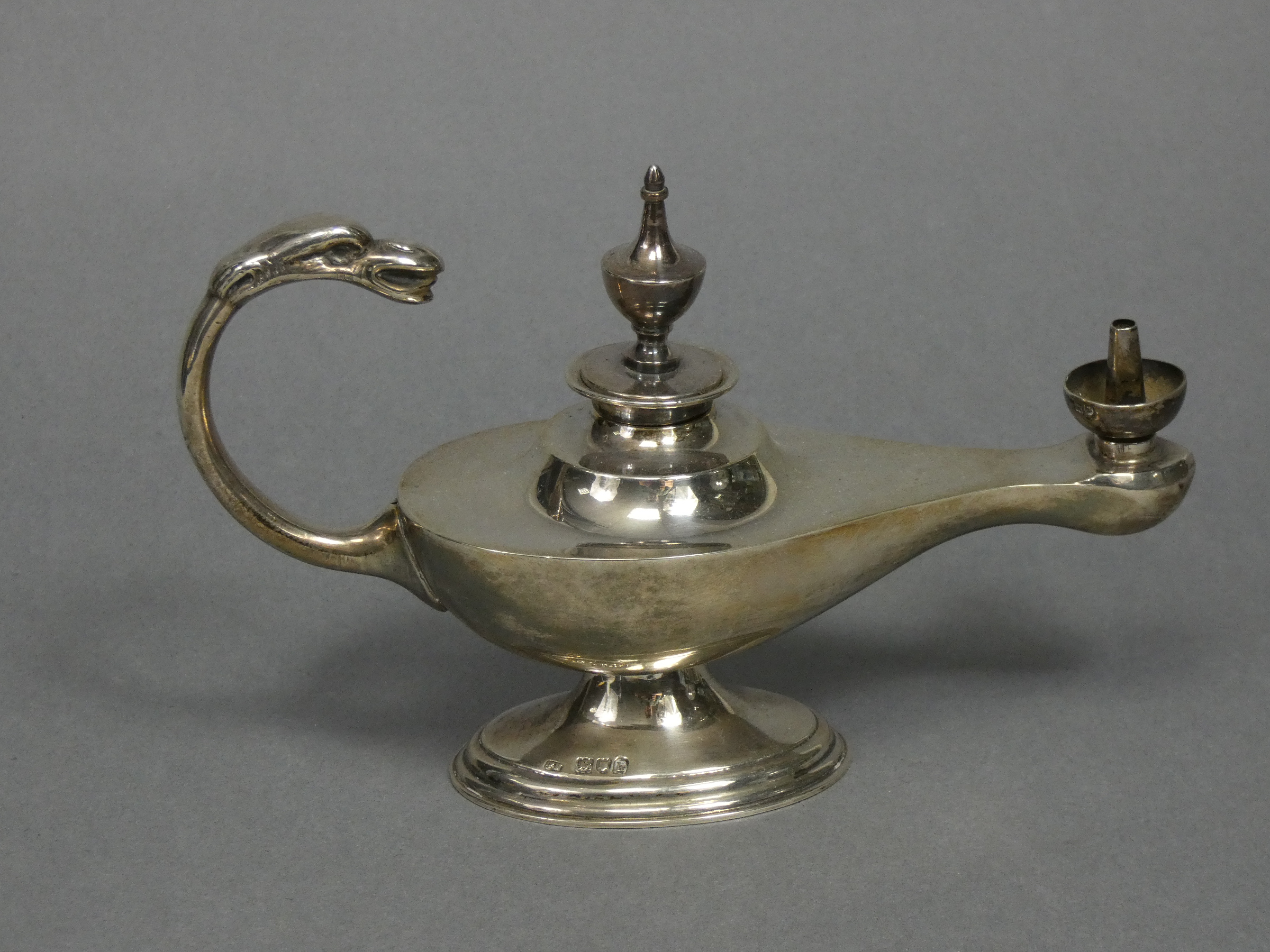 An Edwardian silver table cigar lighter in the form of a roman oil lamp with urn finial & mythical