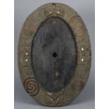 An antique Maori carved wooden oval plaque with stylised decoration & mother-o’-pearl inlaid