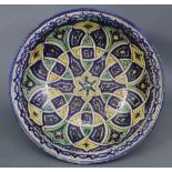 A Persian pottery large shallow bowl, decorated in blue, yellow, green, & white, with repeating