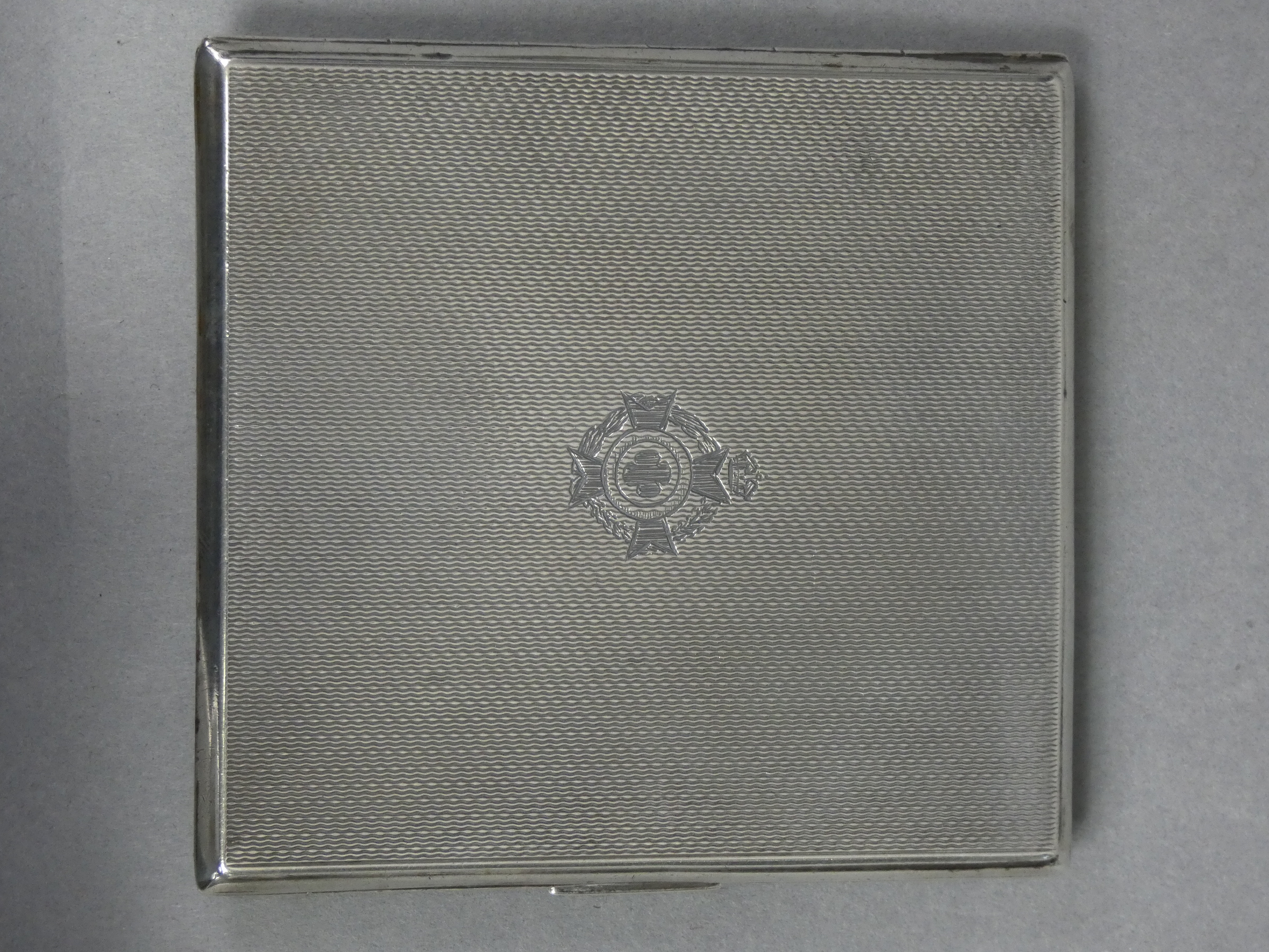 A silver engine-turned pocket cigarette case with engraved Army Chaplain’s badge, the interior