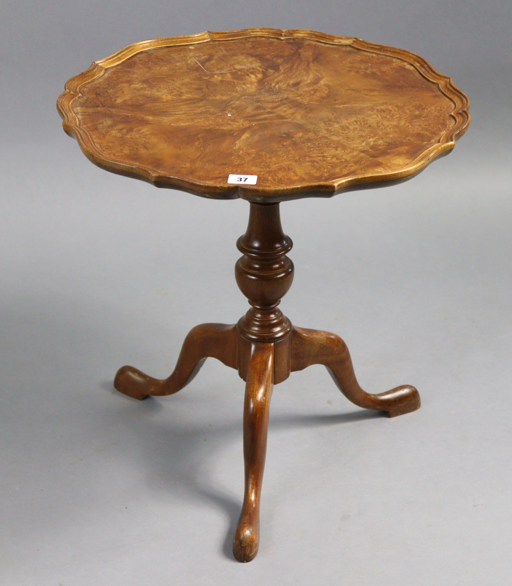 A reproduction walnut tripod table with moulded pie-crust edge to the circular top, & on vase-turned