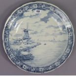 A Delft pottery blue & white charger with river scene decoration having windmill to the foreground &