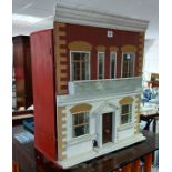 A painted wooden two-storey doll’s house with opening front, 20” wide x 23½” high x 10” deep;