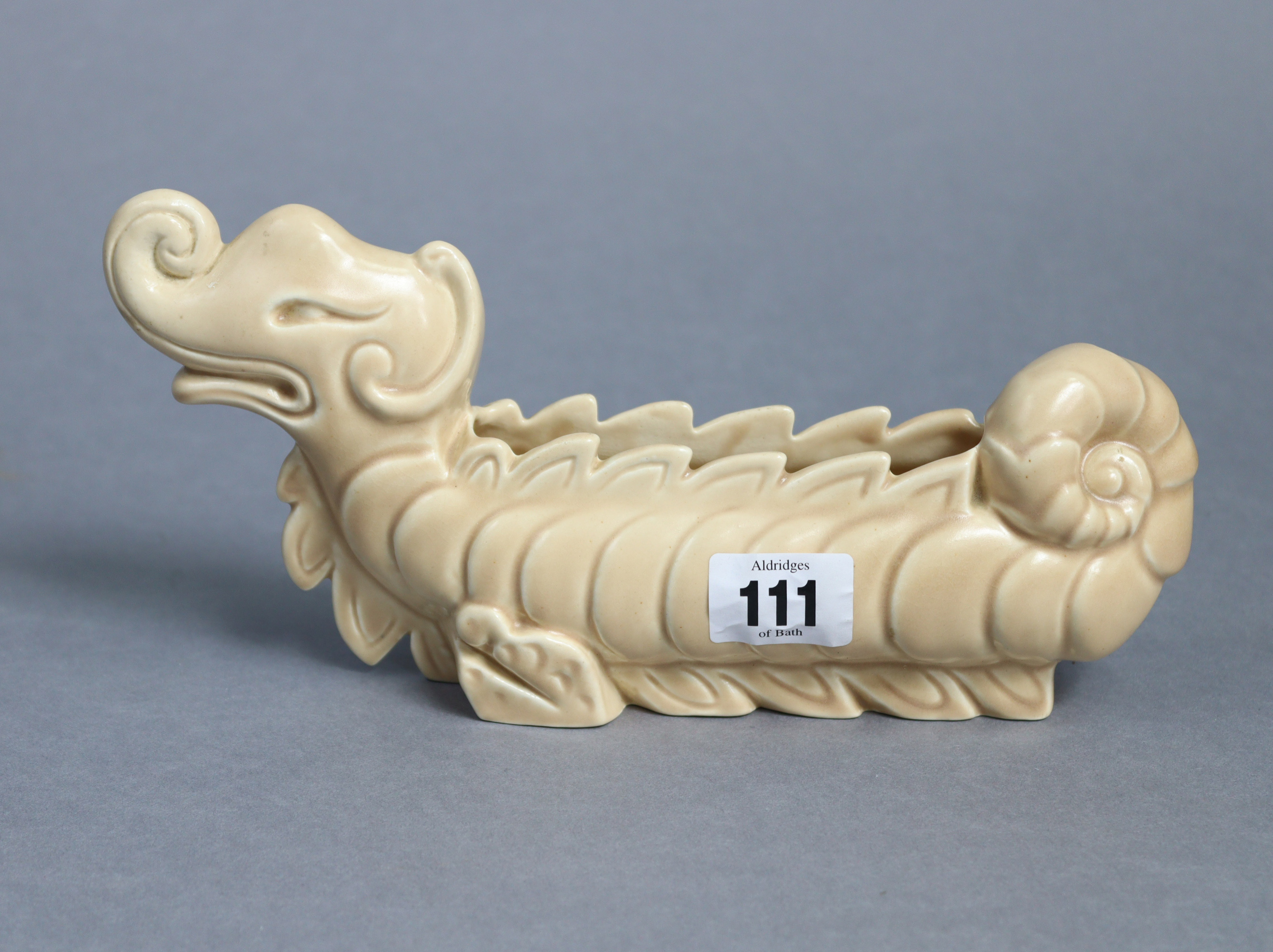 A Clarice Cliff pottery fawn glazed novelty flower trough in the form of a dragon (No. 827), 9½”