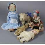 A mid-20th century golden plush teddy bear, 12” tall (worn); a dog soft toy; & three various dolls.