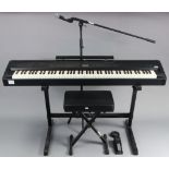 A Roland “FP-80” digital piano with travelling case, stool, & various other accessories including an