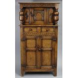 A reproduction small carved oak court-cupboard the upper part enclosed by a centre panel door