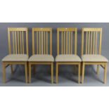 A set of four beech rail-back dining chairs with padded seats, & on square tapered legs.