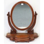 An early 20th century mahogany oval swing toilet glass with a hinged compartment to the serpentine-