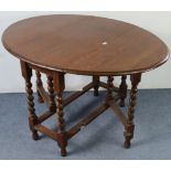 A 1930’s oak oval gate-leg dining table with barley-twist legs & turned feet with plain