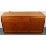 A teak low sideboard fitted with an arrangement of cupboards & a long drawer, on a plinth base, 54½”