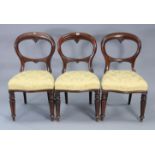 A set of three Victorian mahogany balloon-back dining chairs with padded seats, & on fluted & turned