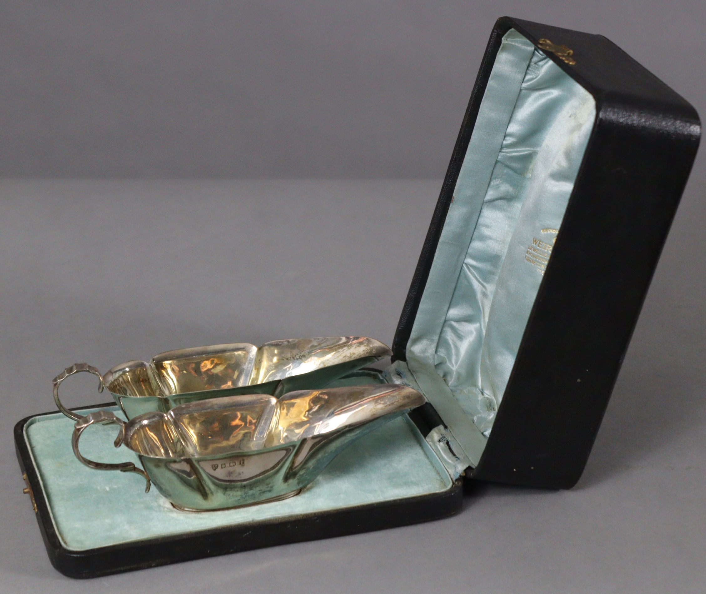 A pair of Edwardian silver sauce boats of slender octagonal form, each with cut-card rims, scroll