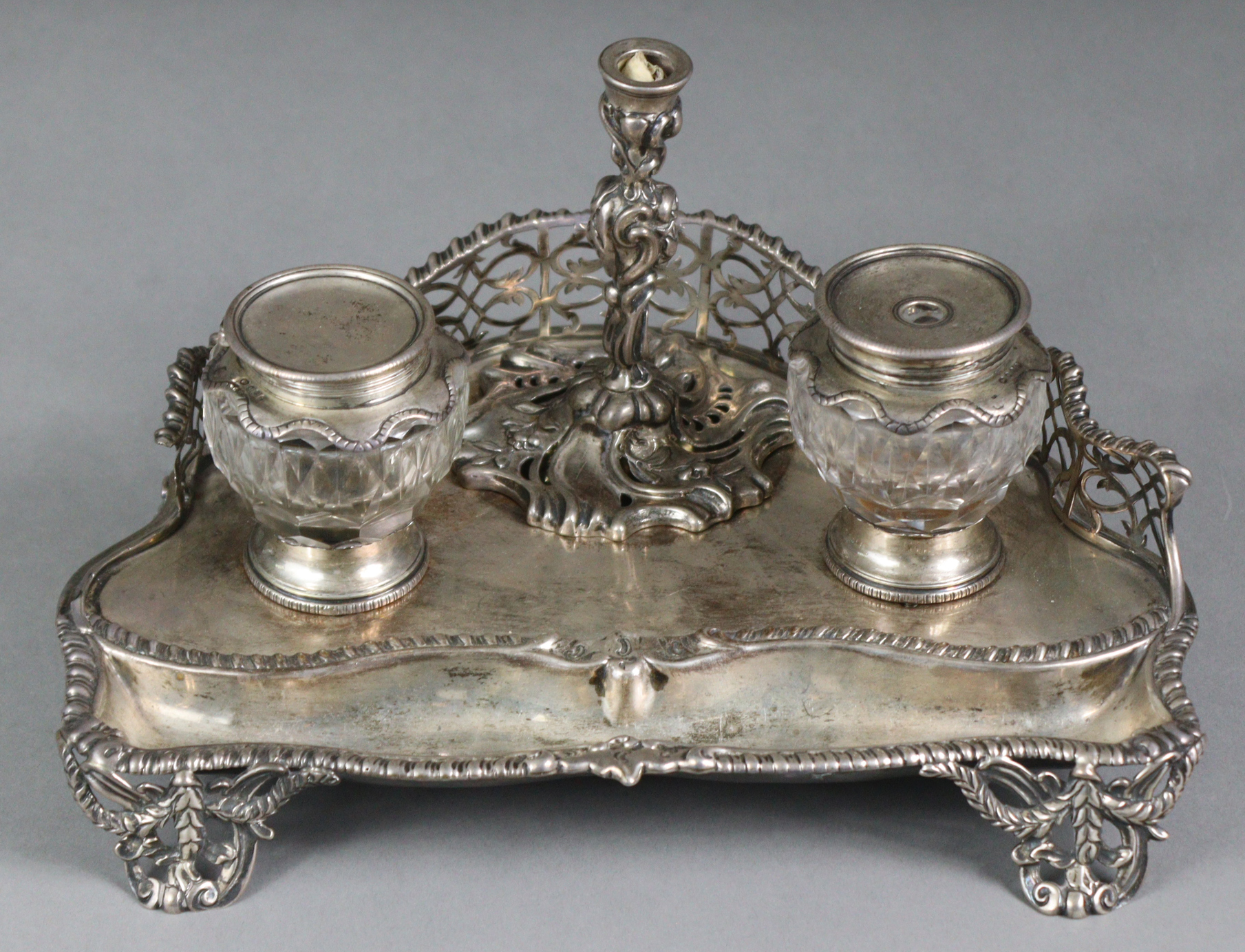 A Victorian silver inkstand of serpentine shape, with pierced gallery, fitted two glass inkwells