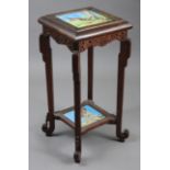 A late Victorian carved beech two-tier lamp table inset two humorous painted tiles, depicting