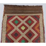 A Suzni kilim runner of madder ground, with brightly coloured repeating geometric design within a