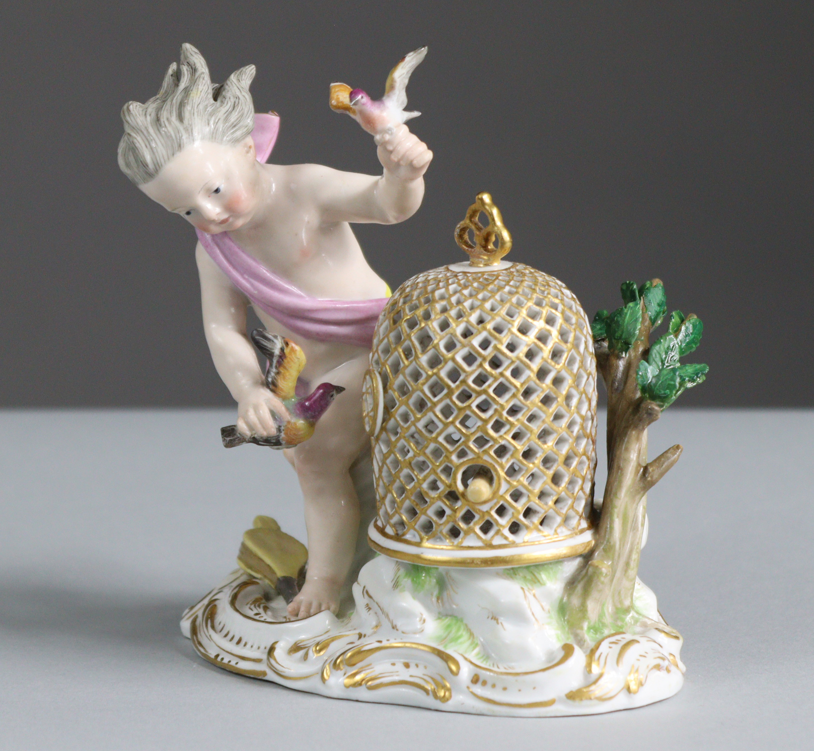 A Meissen porcelain figure of a putto with birdcage & birds, representing the element of Air, on