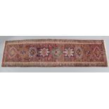 A Persian runner of pink ground with multicoloured repeating geometric design within a narrow
