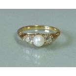 An 18ct gold ring set cultured pearl of approx. 5.5mm dia., flanked by a diamond either side, each