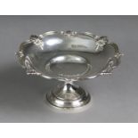 A silver circular sweetmeat dish with embossed shell & swag decoration to the shaped rim, on