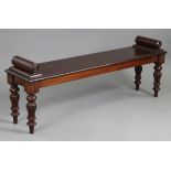 AN EARLY VICTORIAN MAHOGANY HALL BENCH, with turned bolsters to each end, on fluted baluster legs,