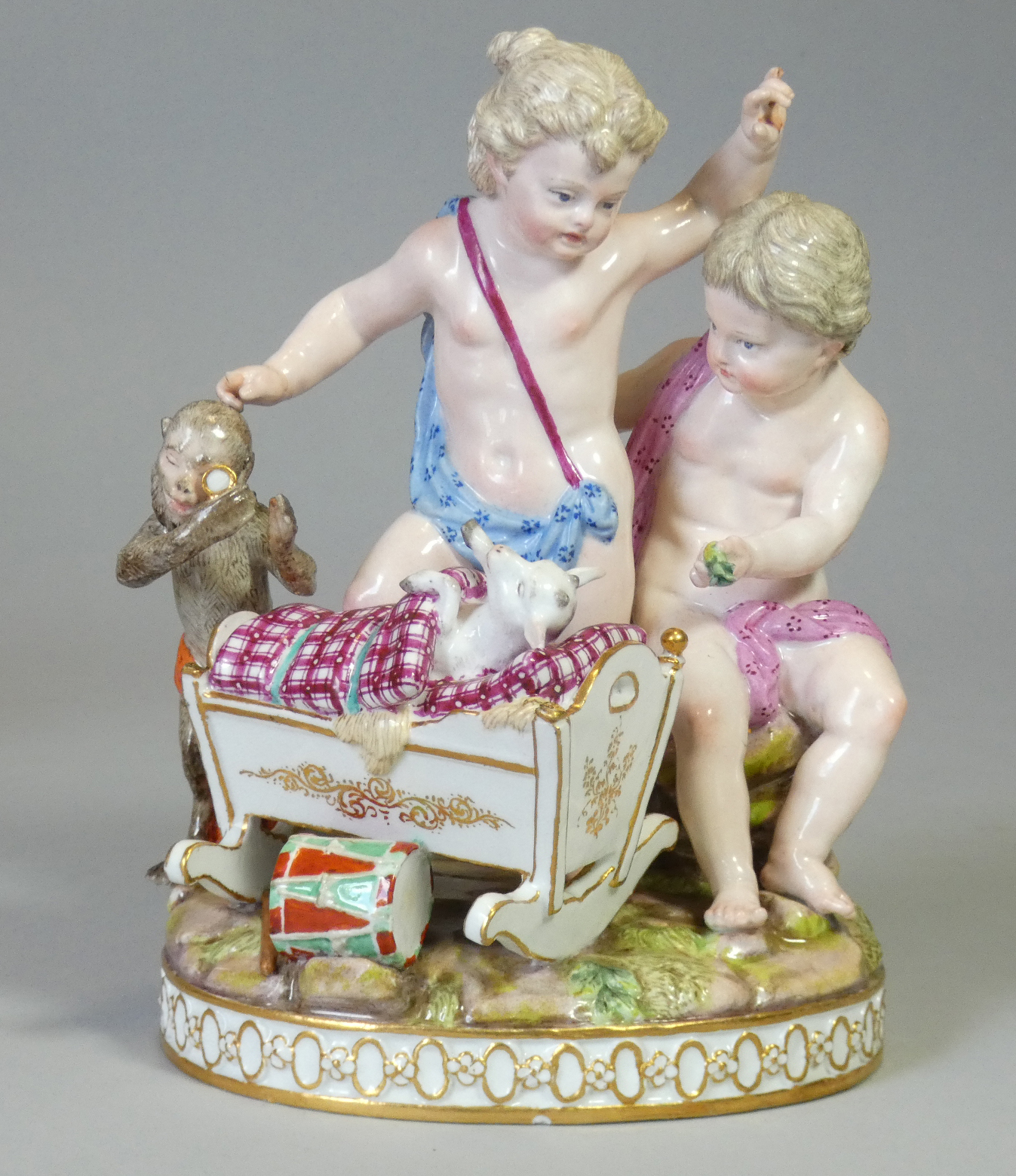 A Meissen porcelain figure group after Schönheit of ‘Two putti playing with a cradle and a monkey