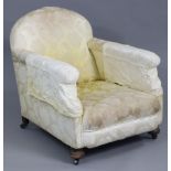 An Edwardian low armchair with rounded back, upholstered yellow floral silk, on bun feet with